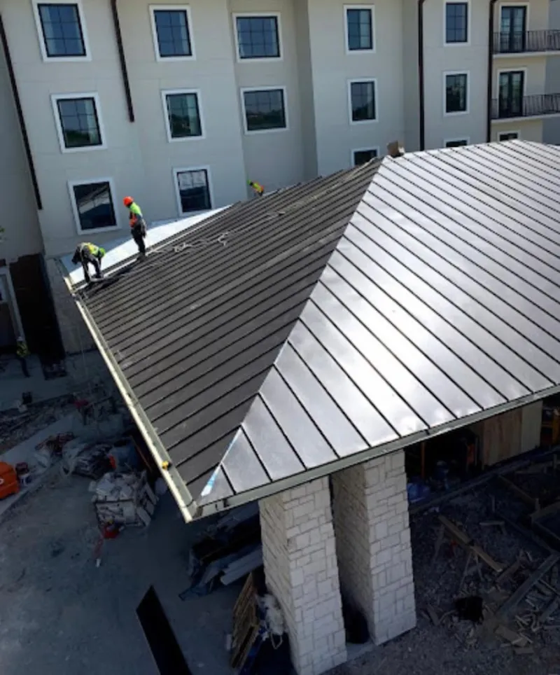 Crew installing standing seam metal roof panels on a commercial project in Maine